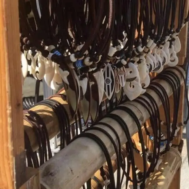 Surfer trägt Lederkette mit Surfbrett Anhänger am Strand