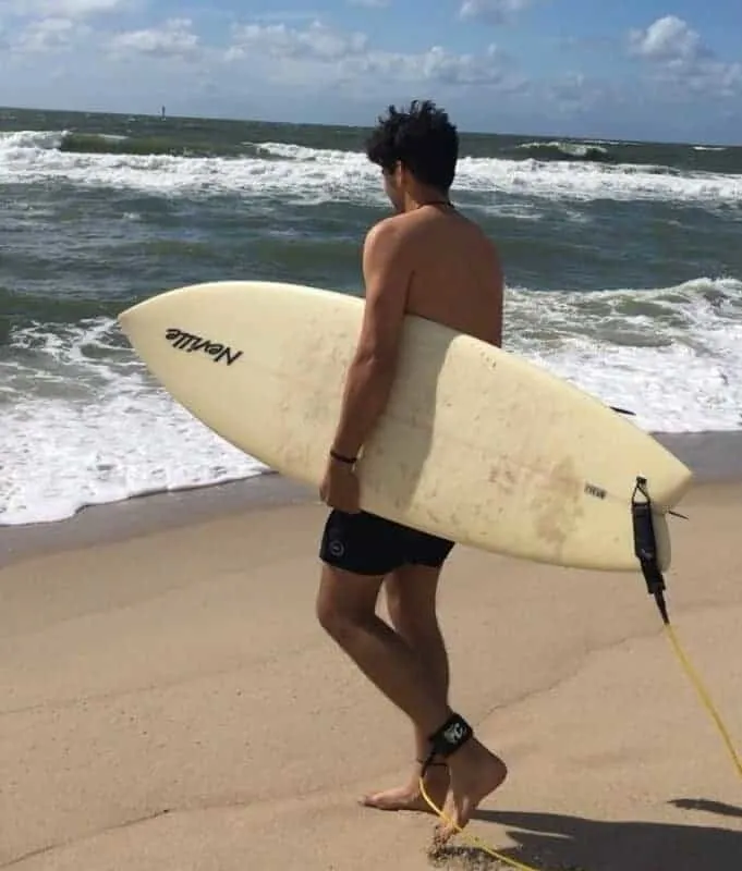 Surfer trägt Lederkette mit Surfbrett Anhänger am Strand